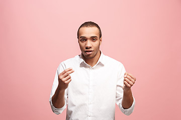 Image showing Beautiful male half-length portrait isolated on pink studio backgroud. The young emotional surprised man