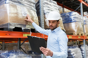 Image showing businessman in helmet with clipboard at warehouse