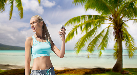 Image showing woman with smartphone doing sports over beach