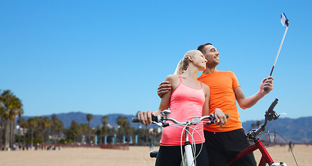 Image showing couple with bicycle and smartphone selfie stick