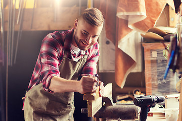 Image showing carpenter working with plane and wood at workshop