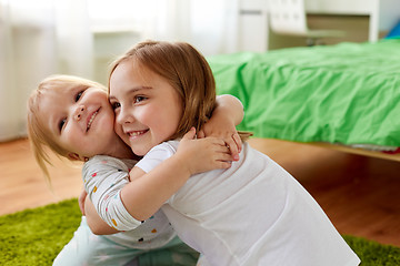 Image showing happy little girls or sisters hugging at home