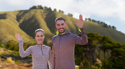 Image showing smiling couple in sport clothes waving hand