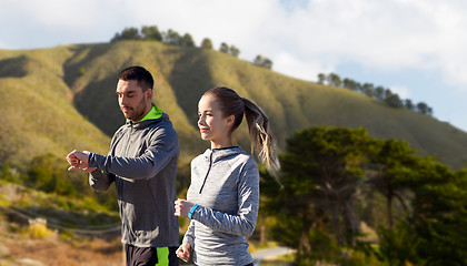 Image showing couple with fitness trackers running outdoors