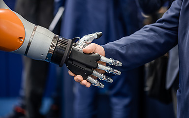 Image showing Hand of a businessman shaking hands with a Android robot.