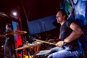 Image showing Drummer playing on drum set on stage.