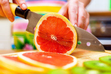 Image showing Women\'s hands Housewives cut with a knife fresh grapefruit on th