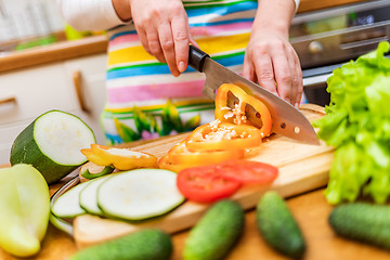 Image showing Female hands of housewife with a knife cut fresh bell pepper on 