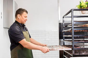 Image showing man with smoking tray at fish shop or smokehouse