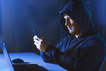 Image showing hacker with laptop and smartphone in dark room