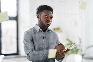 Image showing businessman with clipboard at office glass wall