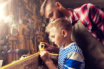 Image showing father and son with ruler measure wood at workshop