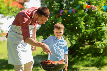 Image showing father and son cooking meat on barbecue grill