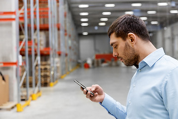 Image showing businessman with smartphone at warehouse