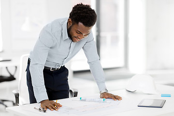 Image showing smiling african architect with blueprint at office