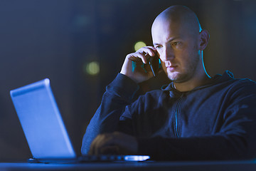 Image showing hacker with laptop calling on cellphone