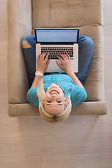 Image showing Young woman using laptop at home top view