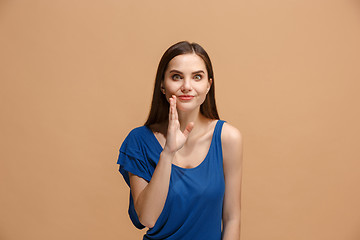 Image showing The young woman whispering a secret behind her hand over pastel background