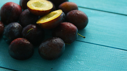 Image showing Purple plums on blue wood