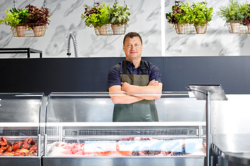 Image showing male seller with seafood at fish shop fridge