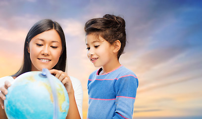 Image showing happy mother and daughter with globe over sky