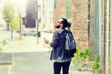 Image showing man with earphones and smartphone walking in city