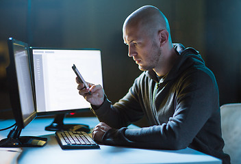 Image showing hacker with smartphone and computers in dark room