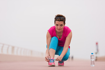 Image showing Young woman tying shoelaces on sneakers