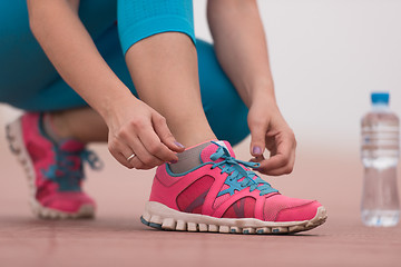 Image showing Young woman tying shoelaces on sneakers