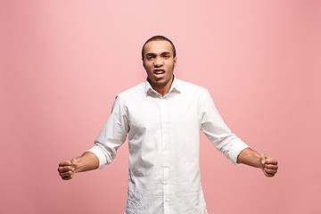 Image showing The young emotional angry man screaming on pink studio background