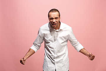 Image showing The young emotional angry man screaming on pink studio background