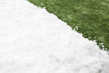 Image showing Meeting snow on green grass close up - between winter and spring concept background