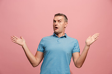 Image showing The young attractive man looking suprised isolated on pink