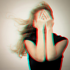 Image showing one sad woman standing near a wall and holding her head in her h