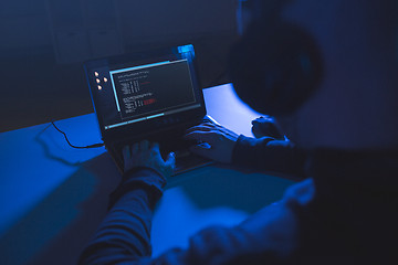 Image showing hacker with coding on laptop computer in dark room