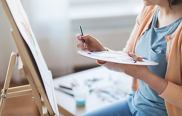 Image showing artist with palette and brush painting at studio