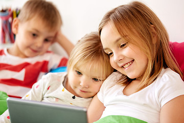 Image showing happy little kids with tablet pc in bed at home