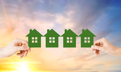 Image showing man and woman hands with many green paper houses