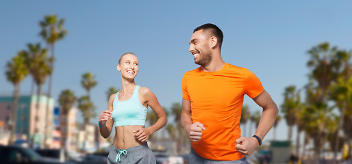 Image showing smiling couple jogging at summer over venice beach