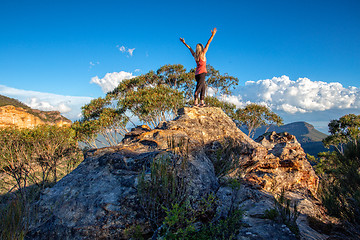 Image showing Standing at the top of a rocky cliff arms outstretched achieveme