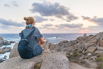 Image showing Solo young female traveler watches a beautiful sunset on spectacular rocks of Capo Testa, Sardinia, Italy.