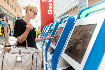 Image showing Casual caucasian woman using smart phone application and check-in machine at the airport getting the boarding pass.