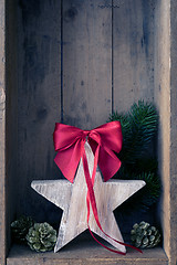 Image showing Christmas decoration red ribbon on a star in a wooden box backgr