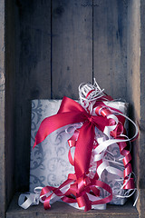 Image showing Christmas present with a red ribbon in a wooden box background