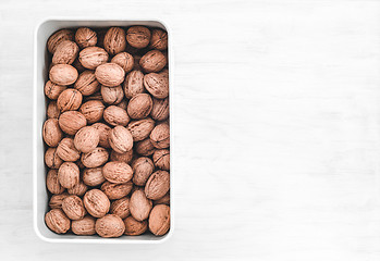Image showing Box full of walnuts on white wooden background