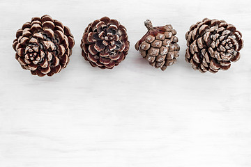 Image showing Four pine tree cones on white wooden background
