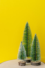 Image showing Christmas decoration three fir trees in front of a yellow backgr