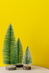 Image showing Christmas decoration three fir trees in front of a yellow backgr