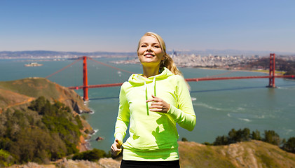 Image showing smiling woman running over golden gate bringe