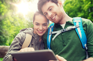 Image showing happy couple with backpacks and tablet pc outdoors